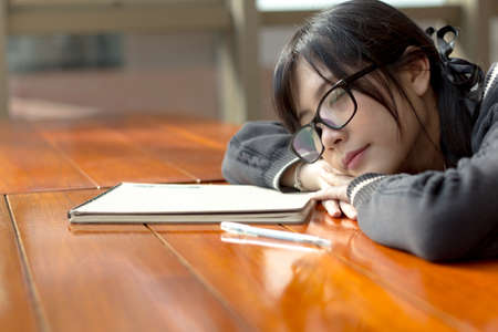 Asian girl in uniform sleepy in libraryの写真素材