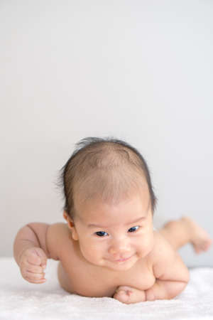 Asian baby lying on stomach and raising his headの写真素材