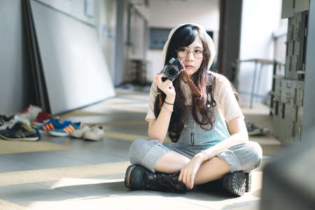Portrait of charming Asian girl with camera in film color style