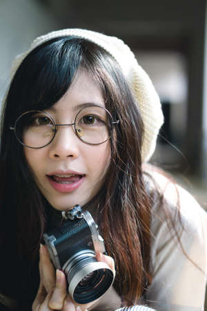 Portrait of charming Asian girl with camera in film color styleの写真素材
