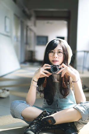 Portrait of charming Asian girl with camera in film color styleの写真素材