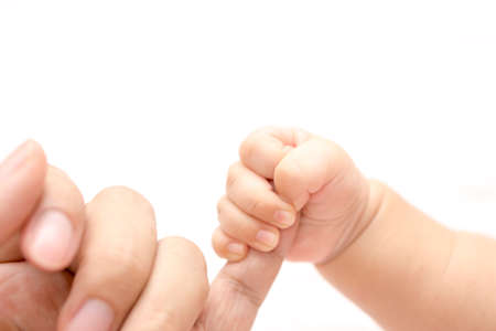 A small baby hand holding a finger