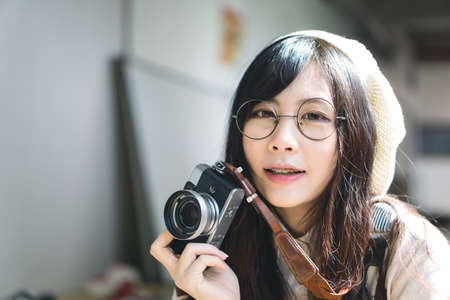 Portrait of charming Asian girl with camera in film color styleの写真素材