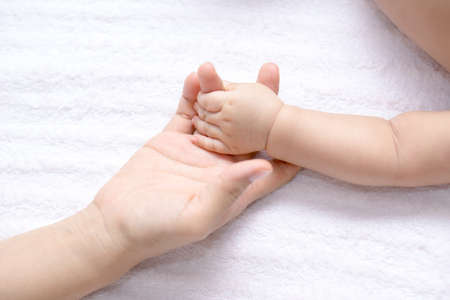 A small baby hand holding a finger