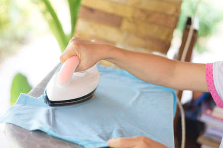 hand of woman ironing clothes on the tableの写真素材