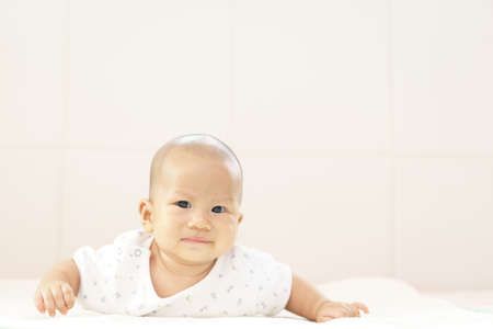 Crying Asian baby lying on stomach and raising his headの写真素材