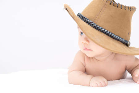 Asian baby with cowboy hat lying on stomach and raising his headの写真素材