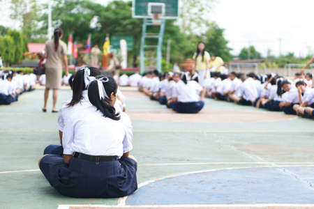 Thai students sit on the floor for school morning announceの写真素材