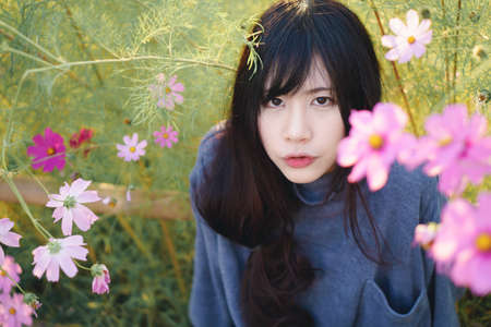 Charming Asian girl with beautiful Cosmos flowerの写真素材