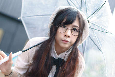 Charming Asian girl with umbrella in raining day