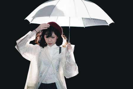 Charming Asian girl  with umbrella and raincoat at night