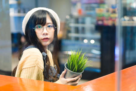 Charming Asian girl holding pot with a plant .
