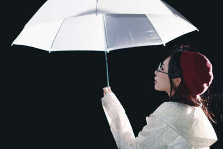 Charming Asian girl  with umbrella and raincoat at night
