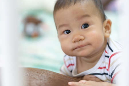 Asian baby playing in the bed surrounded by plastic pipe