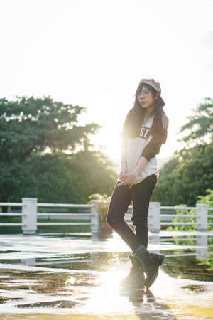 Charming Asian girl in hip hop style with sunset as background