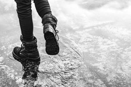 Girl wearing jeans and black combat boots splashing in a puddle after rainの写真素材