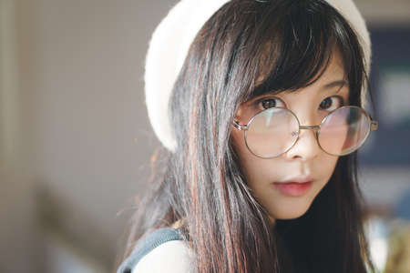 Portrait of charming Asian girl with hat and glasses in film tone styleの写真素材