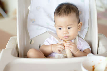 7 months old Asian baby eating fruit for the first timeの写真素材