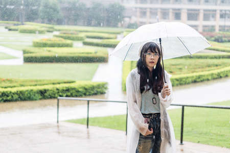 Charming Asian girl  with umbrella and raincoat on raining dayの写真素材