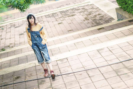 Charming Asian girl wearing jean overalls in the parkの写真素材