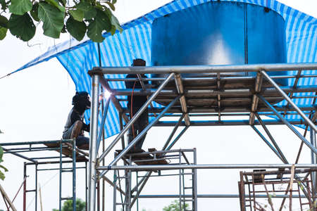 Thai labor welding on steel pipe for making  water tankの写真素材