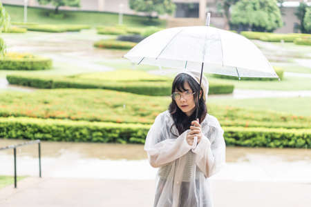 Charming Asian girl  with umbrella and raincoat on raining day
