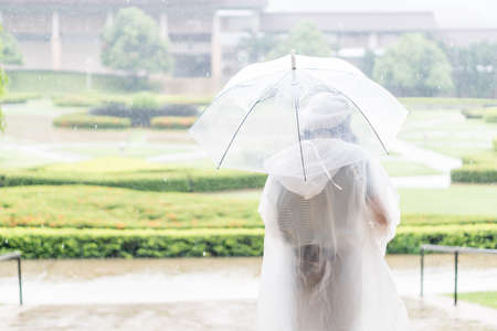 Charming Asian girl  with umbrella and raincoat on raining day