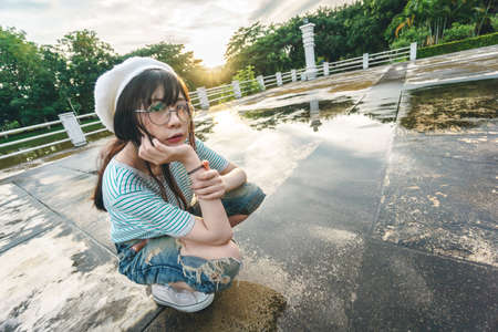 Charming Asian girl wearing jean overalls with sunset as backgroundの写真素材