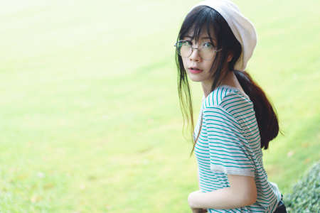 Portrait of charming Asian girl wearing jean overalls in the parkの写真素材
