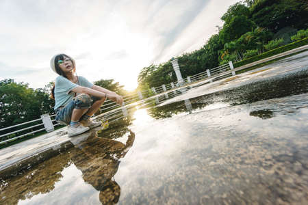 Charming Asian girl wearing jean overalls with sunset as backgroundの写真素材