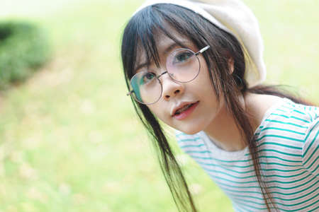 Portrait of charming Asian girl wearing jean overalls in the parkの写真素材