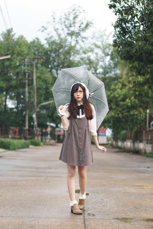 Charming Asian girl with umbrella in raining dayの写真素材