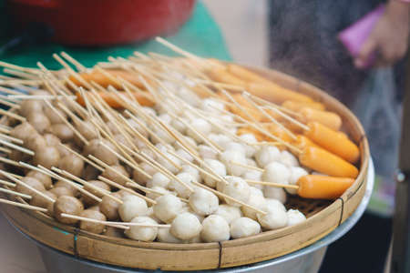 Meat balls and sausages steaming on wooden tray at Thai walking street market