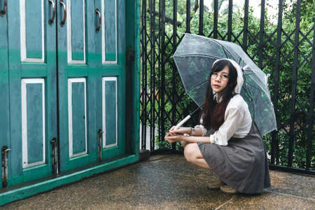 Charming Asian girl with umbrella in raining dayの写真素材