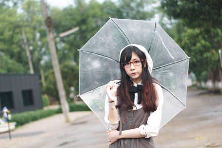 Charming Asian girl with umbrella in raining dayの写真素材
