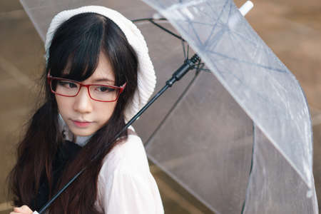 Charming Asian girl with umbrella in raining dayの写真素材