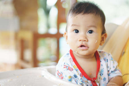 8 months old Asian baby eating food by himselfの写真素材