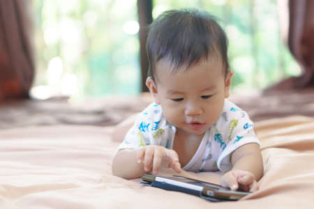 9 months Asian baby playing mobile phoneの写真素材