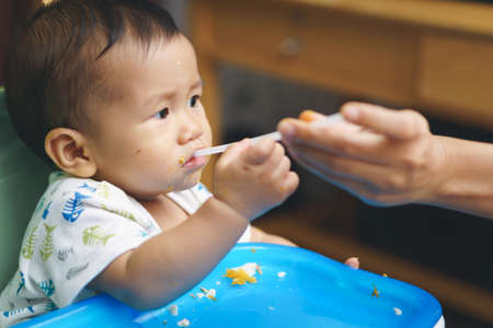 9 months Asian baby drinking water through straw after finish mealの写真素材