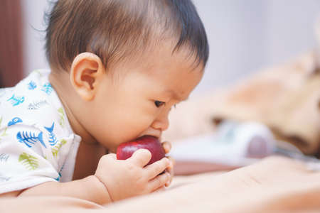 9 months Asian baby eating an apple