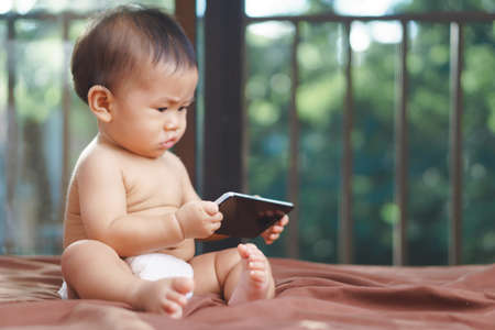 9 months Asian baby playing mobile phoneの写真素材