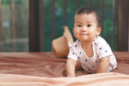 9 months Asian baby playing with hat on the bed