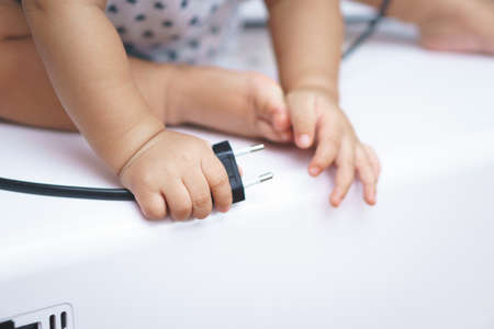 9 months Asian baby curious looking at electronic plugの写真素材
