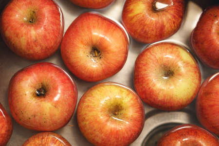 A pile of apples floating in water in a kitchen sinkの写真素材