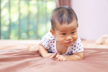 9 months Asian baby playing on the bedの写真素材