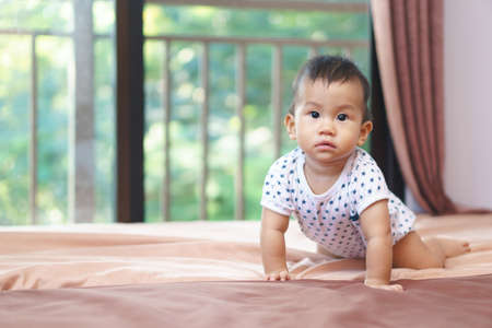 9 months Asian baby playing on the bedの写真素材