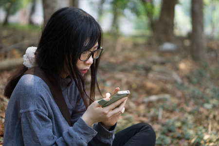 Asian girl looking at her mobile phone with serious expression in film tone colour style