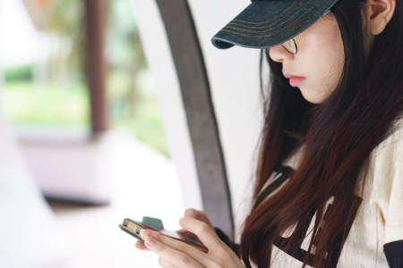 Asian girl looking at her mobile phone with serious expressionの写真素材