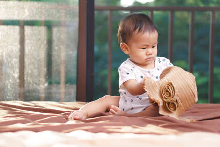 9 months Asian baby playing with hat on the bedの写真素材