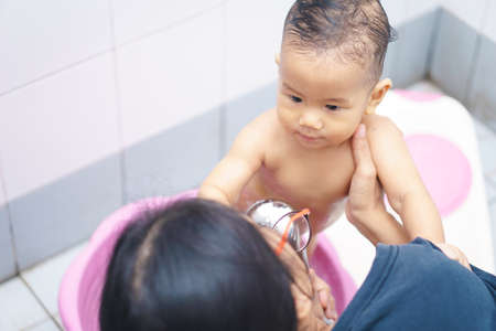 8 months Asian baby showering in bathtub